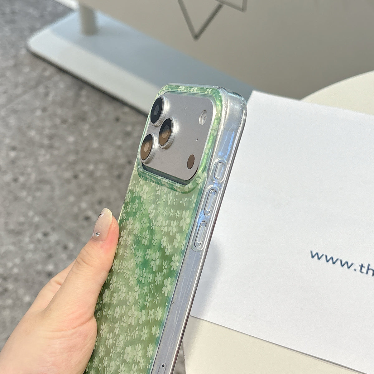 Green textured phone case held by a hand with a blurred background