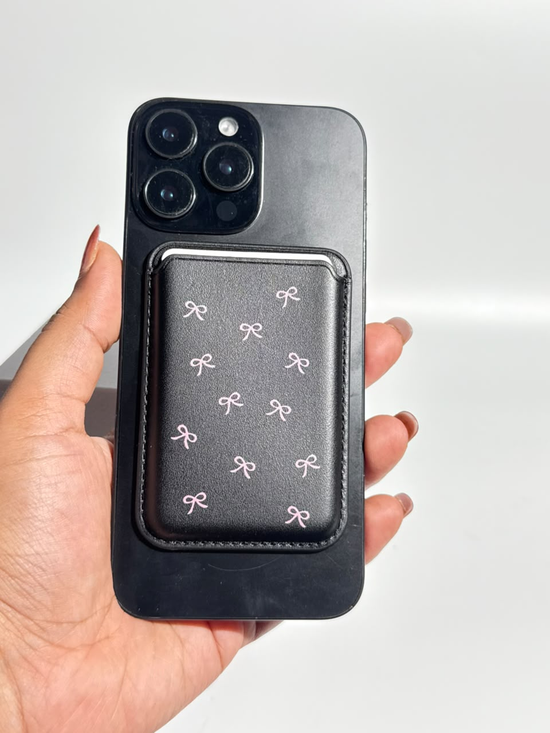 Black MagSafe wallet with pink mini bows on iPhone