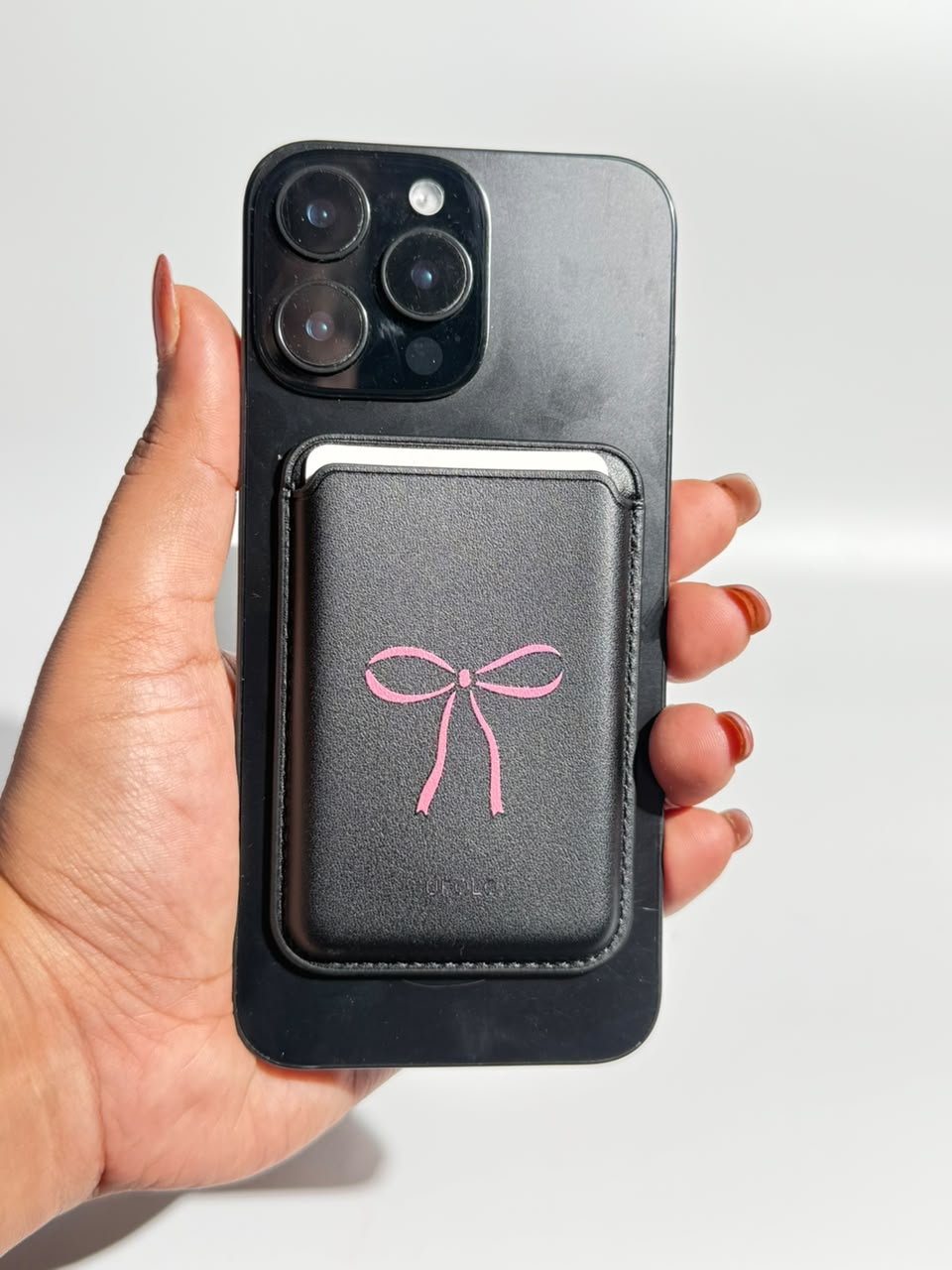 Black MagSafe wallet with pink bow on iPhone