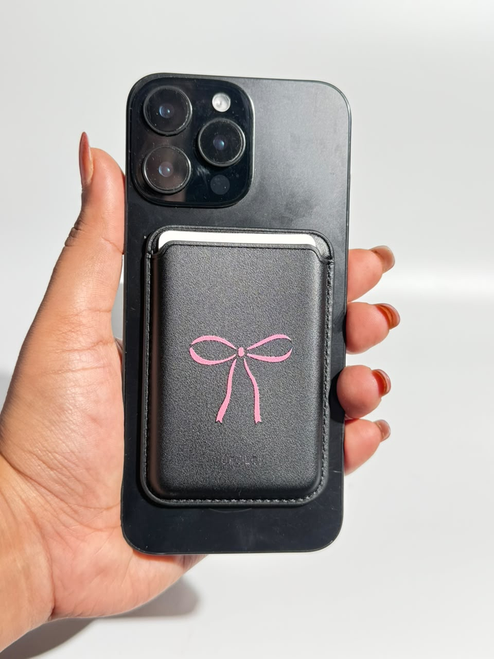 Black MagSafe wallet with pink bow on iPhone